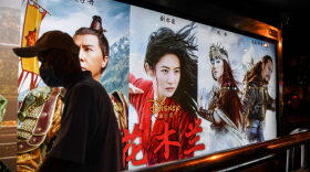 A man walks past a poster of the Disney movie 'Mulan' at a bus stop in Beijing.