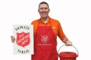 Board member Michael Thomas posing with a red kettle and a Salvation Army sign.