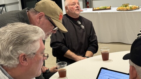 Senator Phil Berger leans over a supporter's tablet to review returns on the night of Primary Elections. After election day ballots were tallied, challenger Sam Page led Berger by two votes with provisional and some additional ballots remaining.