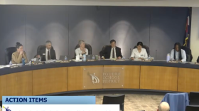 A group of people sit behind a large desk.