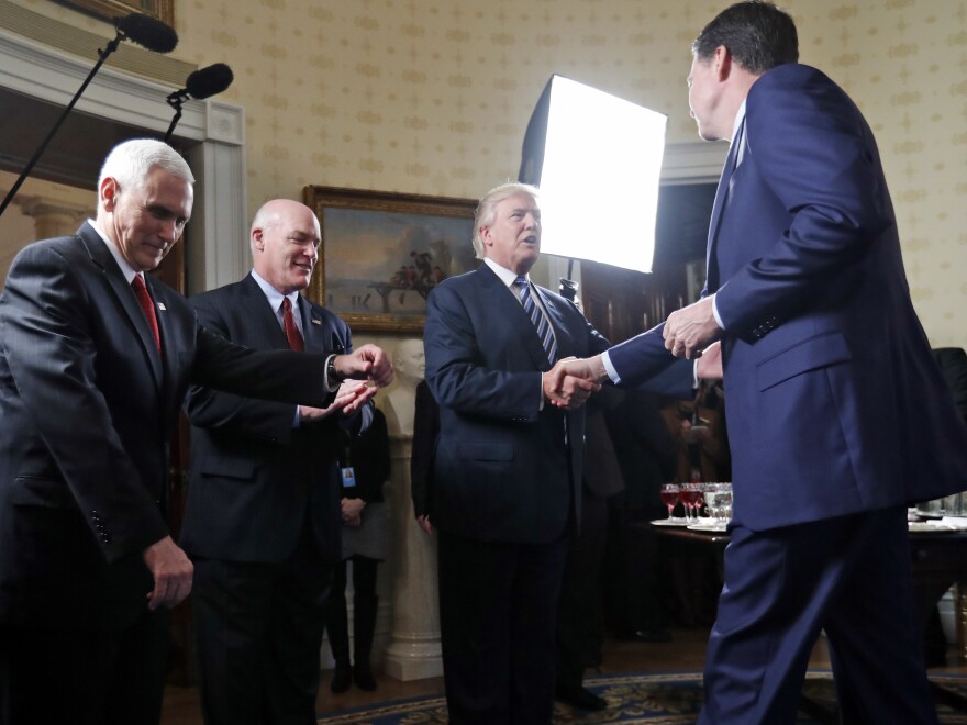 Alongside Vice President Pence (left) and outgoing Secret Service Director Joseph Clancy, President Trump shakes hands with then-FBI Director Comey at the White House on Jan. 22. Comey notes this was a moment he would have rather avoided because of the appearance of impropriety.