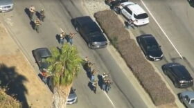 Law enforcement officials walk with weapons drawn outside a Southern California social services center in San Bernardino, Calif., where authorities said multiple people were shot Wednesday, Dec. 2, 2015. (KTTV via AP)