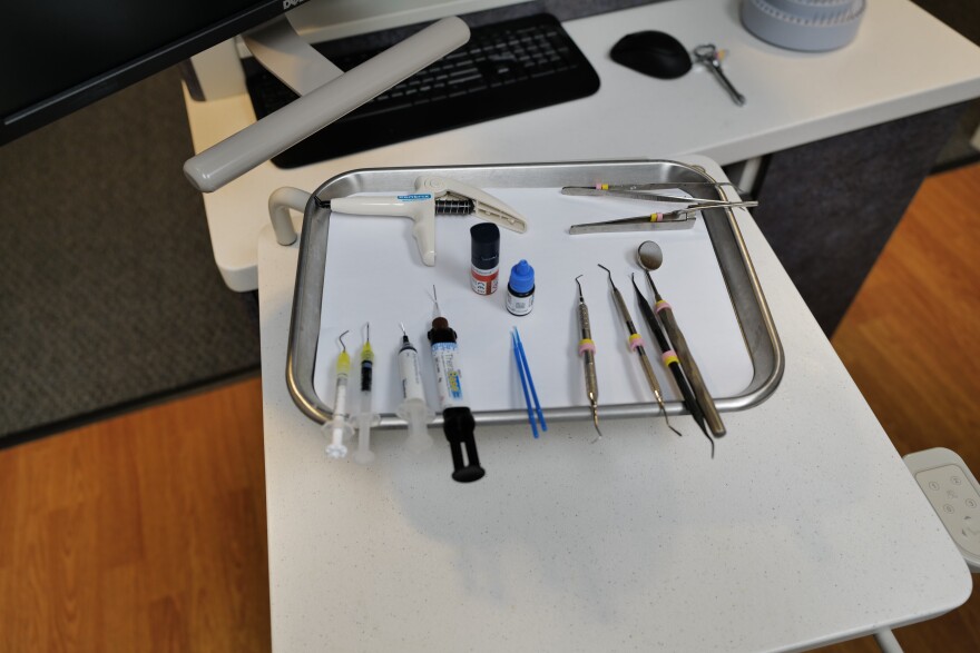 Dental tools used for routine examinations sit on a tray at a dental office.