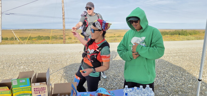 Runners Ron and Jen Johnson with race volunteer Devon Stalker at a checkpoint about three miles from the finish line. Volunteers from Kotzebue's cross country team, the Northwest Arctic Borough, Maniilaq's Diabetes Program, and other organizations operated several checkpoints along the race route. 
