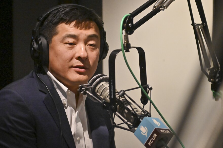 A man inside a radio studio sits at a microphone talking.