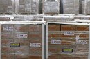 Humanitarian aid is stored in large boxes at a warehouse with labels that read 'USAID' and 'Donación 