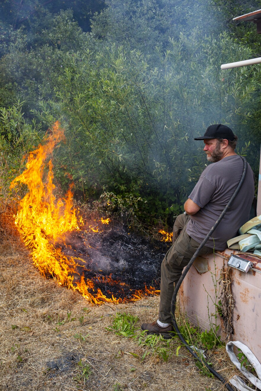 Bill Tripp keeps an eye on a burn near a pump house that supplies water to an Orleans, California neighborhood.