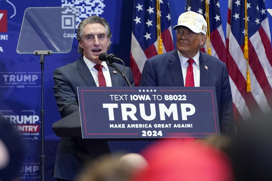 Republican presidential candidate former President Donald Trump listens as North Dakota Gov. Doug Burgum speaks at a rally at Simpson College in Indianola, Iowa on Sunday.