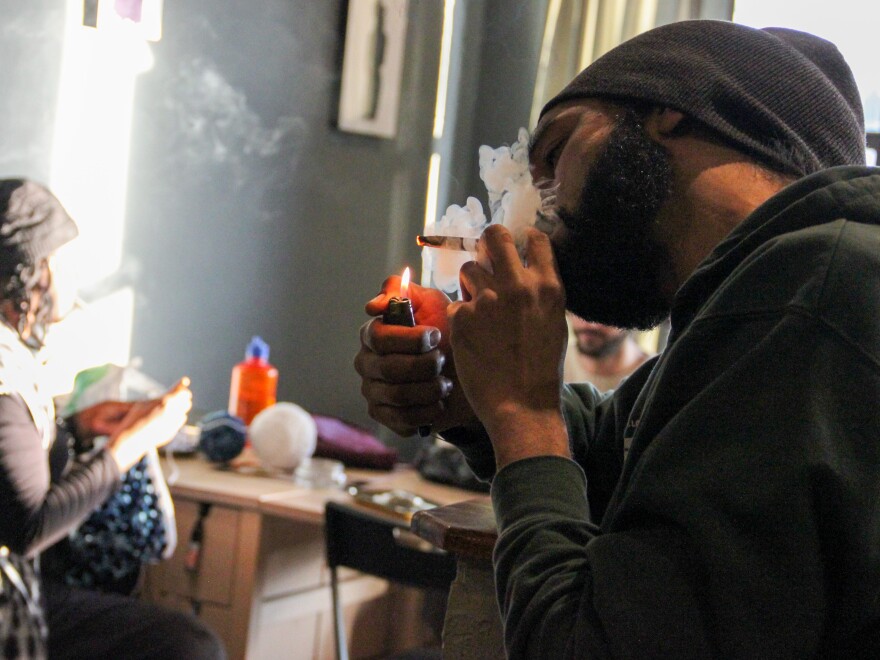 Brennan England, owner of the Cola Private Lounge on Cherokee Street, lights up a blunt. 