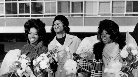 FILE - In this Nov. 3, 1964 file photo, American pop trio Martha Reeves and the Vandellas dance for photographers at an airport in London, arriving for TV appearances and recording work in the British capital. From left are Betty Kelly, Martha Reeves, and Rosalind Ashford. Fifty years after the 1967 Detroit riots, the leader of Martha and the Vandellas still can’t quite believe it happened. “Imagine going out there lighthearted and ready to work,” she said. “My heart was beating so fast after returning to the dressing room.” (AP Photo)