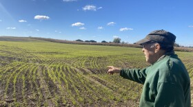 Manitowoc County farmer, Michael Slattery, is pictured in the right side of the photo wearing a green sweatshirt and black hat, as he points toward his field of crops.