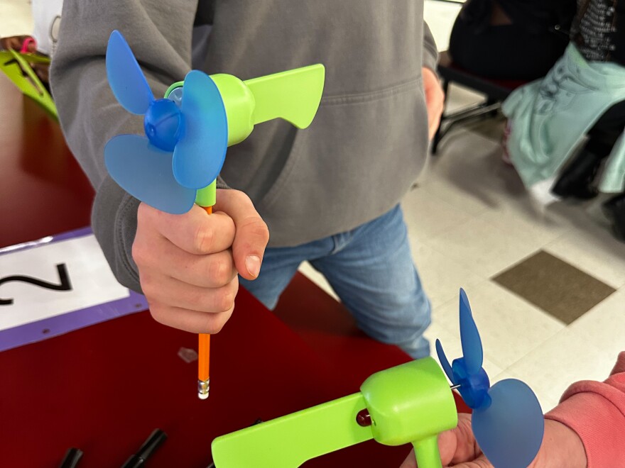 Middle schooler Parker Nixon holds up his miniature wind turbine.