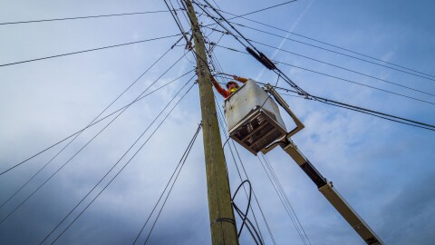 A line worker installs fiber optic cables on electric poles.