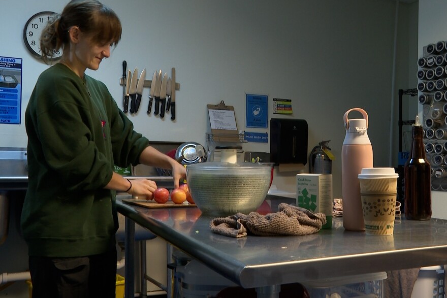 A worker at Mother Hubbard's Cupboard prepares a salad.