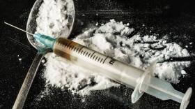 white powder on a black table and in a spoon with a syringe
