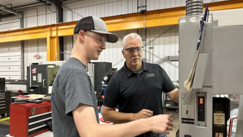Hess Industries founder Mark Hess quizzes an apprentice on his knowledge of a CNC machine.