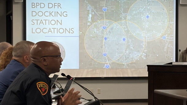 a police chief sits in the foreground, in the background a map shows locations for drone deployment docs in Bloomington