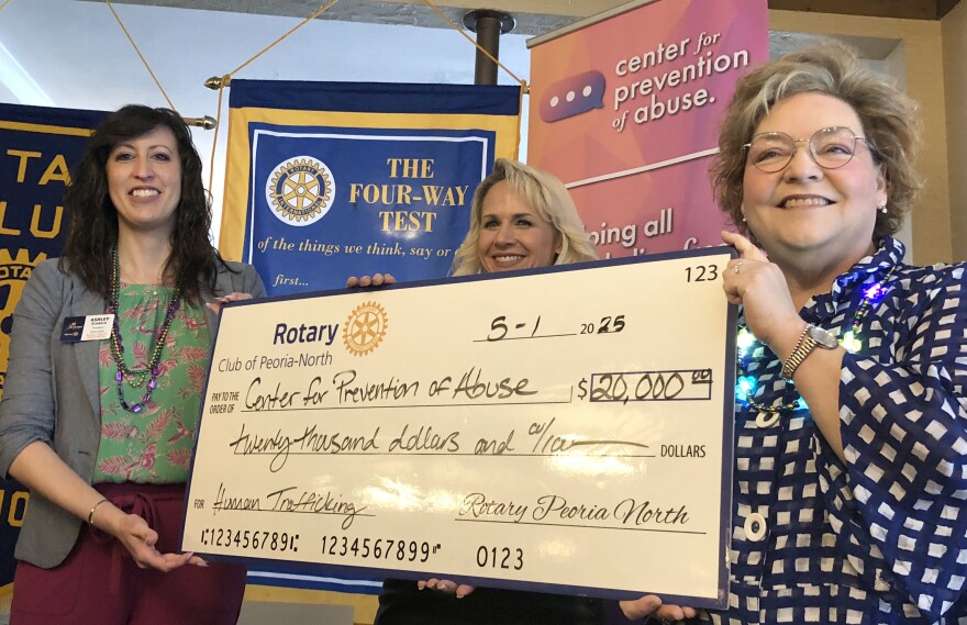 Rotary Club of Peoria North club president Ashley Schreck, left, and fundraising event committee chair Gin Burwitz present an oversized ceremonial check representing a $20,000 grant to Center for Prevention of Abuse CEO Carol Merna.