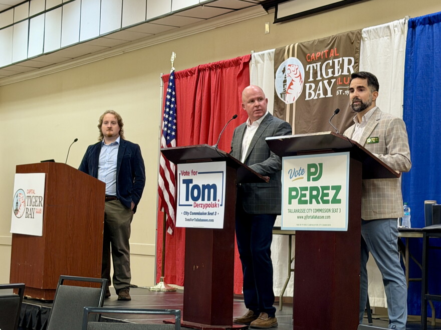 Tallahassee City Commission Seat 3 candidates Tom Derzypolski (center) and PJ Perez (right) participating in a Capitol City Tiger Bay debate moderated by WFSU Public Media reporter Tristan Wood (left) on Sept. 29, 2026.