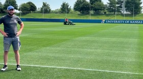 After months of grooming, treating and protecting KU’s Rock Chalk Park women’s soccer pitch, Grounds Maintenance Supervisor for Kansas Athletics James Massey is confident it’s ready to host the Algerian National Football Team for its practices during the 39-day World Cup. In the background, Tanner Fisher drives one of two 15,000-pound John Deere PrecisionCut mowers used to keep the pitch in pristine condition.