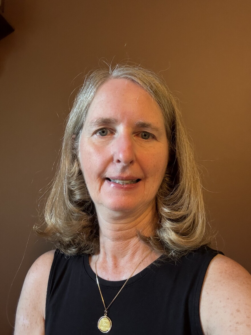 a portrait picture of a woman with light brown hair against a dark brown background 