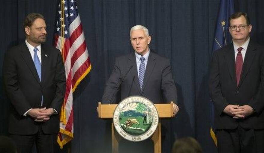 Kent Abernathy, left, the new commissioner of the Indiana the Bureau of Motor Vehicles, and former commssioner Don Snemis, right, listen as Gov, Mike Pence announces he is launching an internal audit of the Bureau of Motor Vehicles and is seeking legislation to streamline the agency's fee structures amid revelations it overcharged motorists another $2 million over six years, at the Indiana State House, Indianapolis, Monday, Feb. 2, 2015.