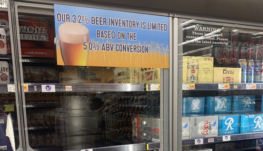 An empty beer cooler cooler with a sign that reads 'our 3.2% beer inventory is limited based on the 5% ABV conversion.