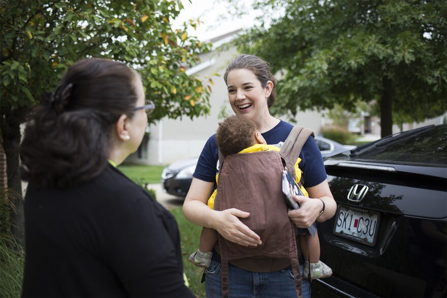 Mary Elizabeth Coleman holds her son Gerhardt while talking to voters and knocking doors in her district last month. Coleman, a lawyer and mother of six, has made her family a big part of her campaign. Oct. 2018