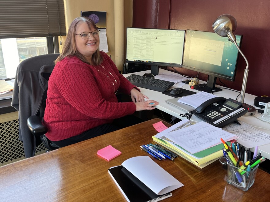 Kathryn Murphy is the Grants and Budget Manager for the City of Peoria's Community Development Office. A woman in a red sweater sits at a desk in front of multiple computer screens.
