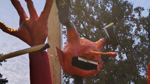 Puppet head made out of paper-mache that's made to look like a devil with Flock Safety camera for eyes.