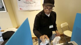 John Davis, a polling judge volunteer, sanitizes an electronic voting machine screen amid concerns about the COVID-19 coronavirus at a polling place in the Bronzeville neighborhood of Chicago, Tuesday, March 17.