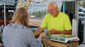 Montgomery County-based grower Gary Cox makes change for a customer in his Trinity Acres Farm tent at the Lafayette Farmers Market.