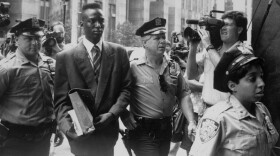 Yusef Salaam, wrongly accused of rape, is escorted by police. He and four other teens were eventually found guilty of a crime they didn't commit.