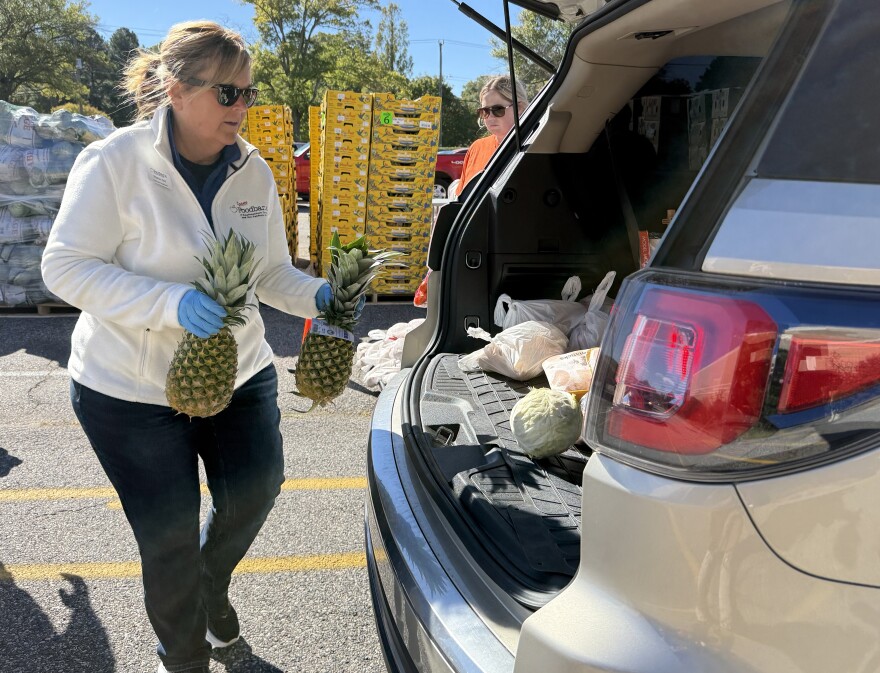 Sharon Dail with the Foodbank of Southeastern Virginia and the Eastern Shore loads groceries into a car at a pop-up food distribution event in Norfolk Oct. 17. The event was one of several in the area that attracted large crowds during the ongoing federal government shutdown.