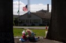 The Washington state flag, American flag and Nippon Dynawave flags fly at half-staff while flowers mark a makeshift memorial on old mill equipment in front of Nippon Dynawave Packaging Co. for the victims of the May 26 chemical disaster, in Longview, Wash., on May 29, 2026.
