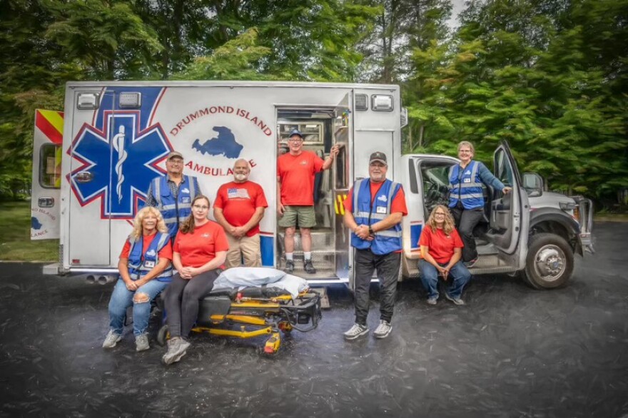 The current Drummond Island EMS volunteers posing with an ambulance vehicle.