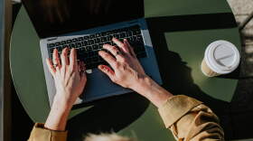 Corporate image of hands typing on a laptop keyboard in an outdoor environment, perhaps a balcony, a garden or a rooftop terrace.