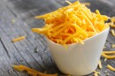 Shredded cheddar cheese in white cup close up