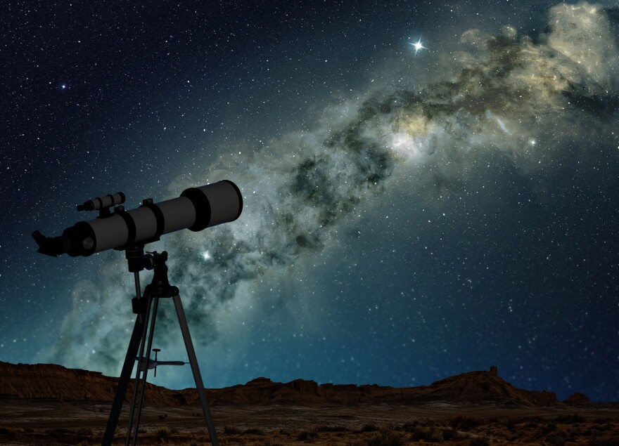 A telescope on a tripod pointed up toward a night sky.