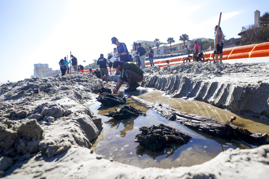 Members of a team of archaeologists study a wooden structure in the sand, Tuesday, Dec. 6, 2022, in Daytona Beach, Fla. Severe beach erosion caused by two late-season hurricanes helped partially uncover what appears to be part of an 80-foot-long (24-meters) ship in the sand on Daytona Beach Shores, officials said.