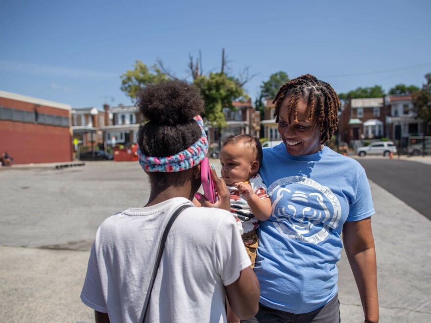 Anderson School Principal Laurena Zeller carries her son through the schoolyard, while students enjoy outdoor activities and games on the last day of the school year.