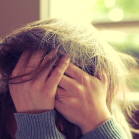 young adult with hands in hair.