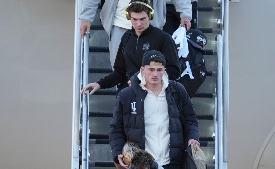 Indiana quarterback Fernando Mendoza, top, walks off the plane with teammates after they arrived at the Indianapolis International Airport in Indianapolis, Tuesday, Jan. 20, 2026.