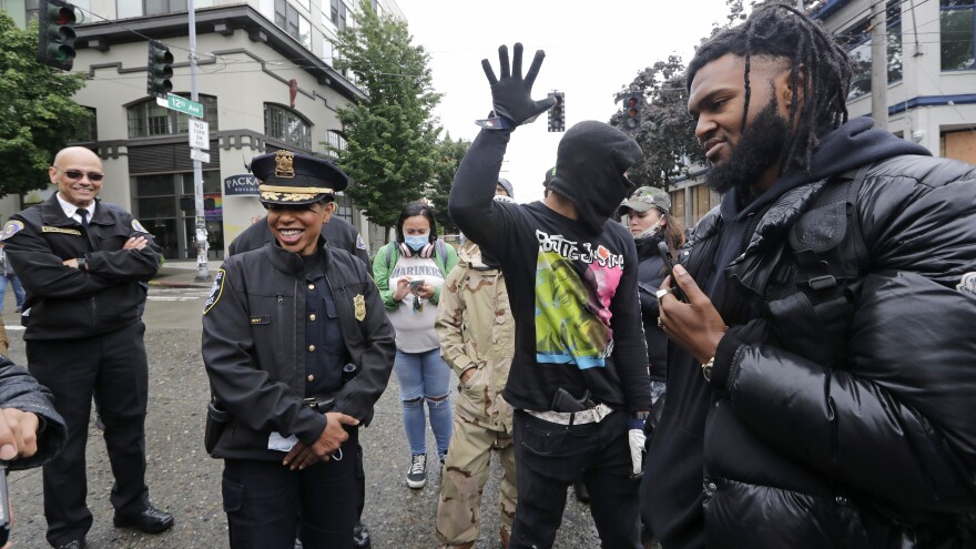 Seattle Police Chief Carmen Best (second from left) talks this week with activists Raz Simone (right) and Keith Brown near the spot in the "Capitol Hill Autonomous Zone" where police had earlier boarded up a precinct building.