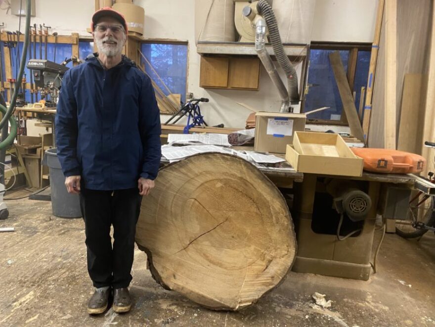 A man stands next to a large section of a tree