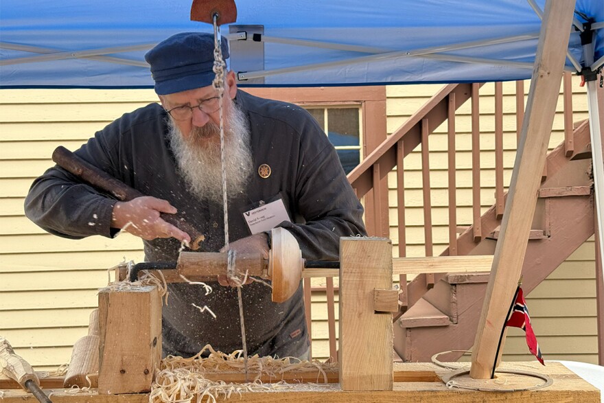 David Susag carves a wooden bowl in a folk art demonstration outside Vesterheim.