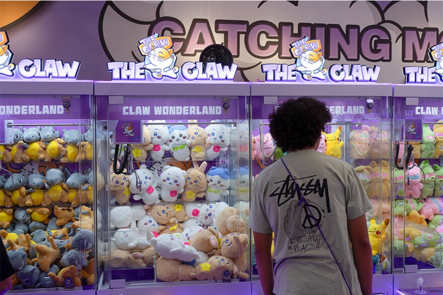 An onlooker stands in front of purple claw machines at The Claw