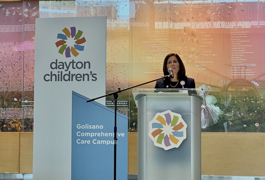 President and CEO of Dayton Children's Hospital, Debbie Feldman, Stands at a podium with a sign marking the hospitals impending name change for its main campus
