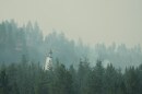 A firefighting helicopter dumps water on a wildfire in the northwest part of Spokane, Wash., Tuesday, Aug. 4, 2026. (AP Photo/Lindsey Wasson)