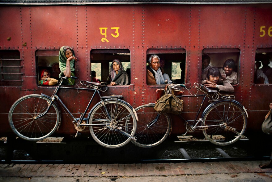 Bicycles hang on the side of a train traveling from Dacca to Peshawar, West Bengal, India. April 1993.